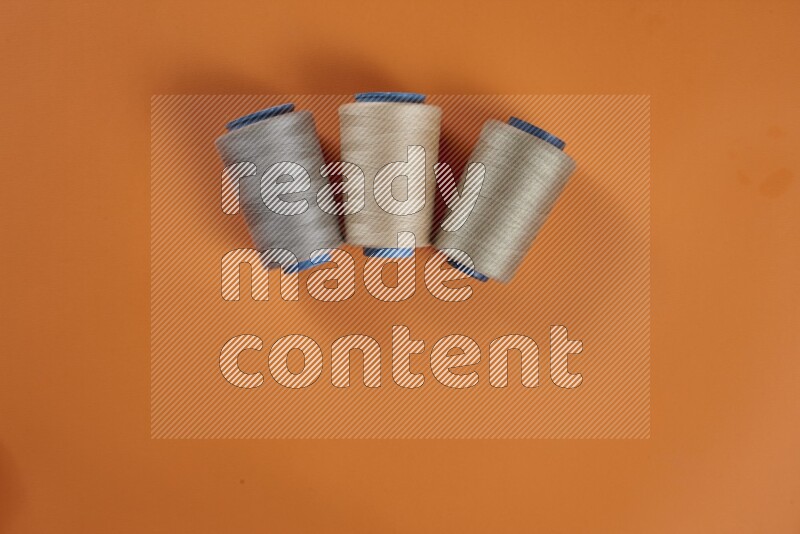 A brown collection of sewing and tailoring tools arranged on a orange background