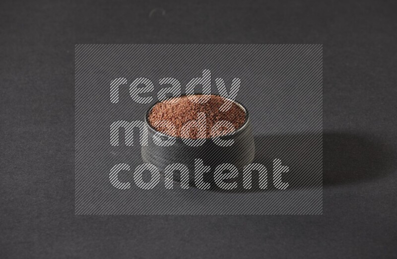 وعاء فخاري أسود ممتلئ ببذور حب الرشاد على أرضية سوداء