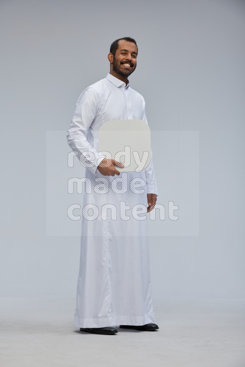Saudi man wearing Thob standing holding social media sign on Gray background