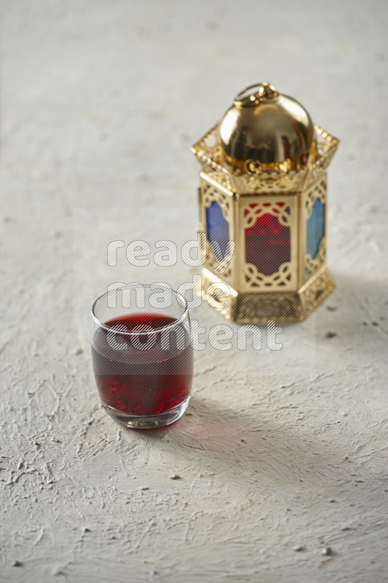 A golden lantern with different drinks, dates, nuts, prayer beads and quran on textured white background