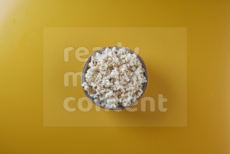 A brown pottery bowl full of popcorn on a yellow background in different angles