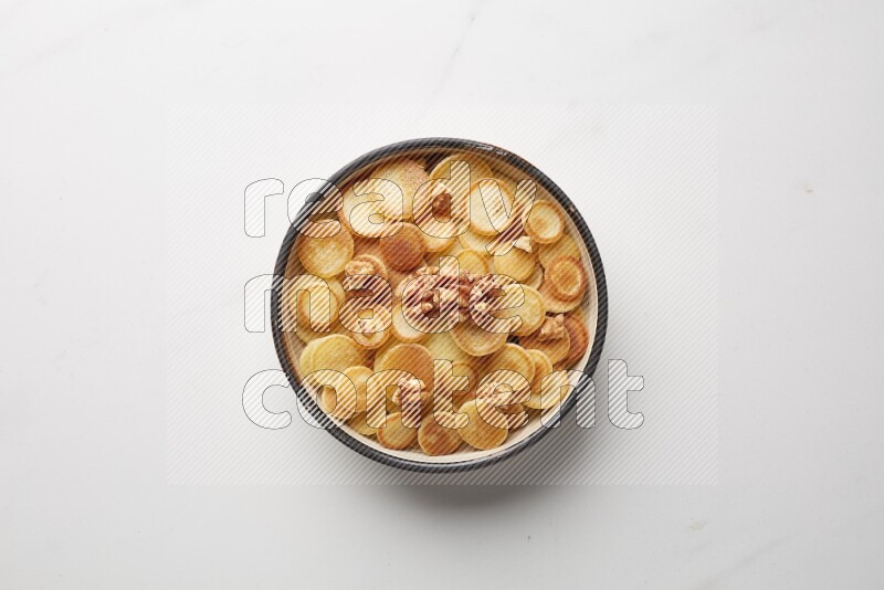 Top-view shot of walnut cereal pancakes in a round bowl on white background