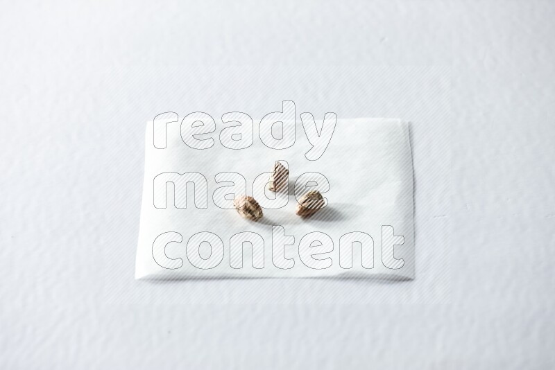3 peeled pistachios on a piece of paper on a white background in different angles