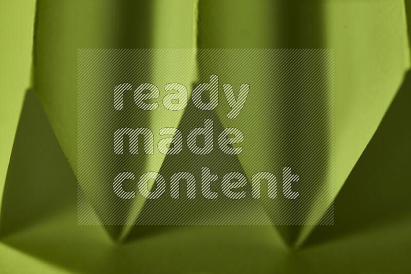 صورة مجردة مقربة تظهر طيات ورقية هندسية حادة بتدرجات اللون الأخضر