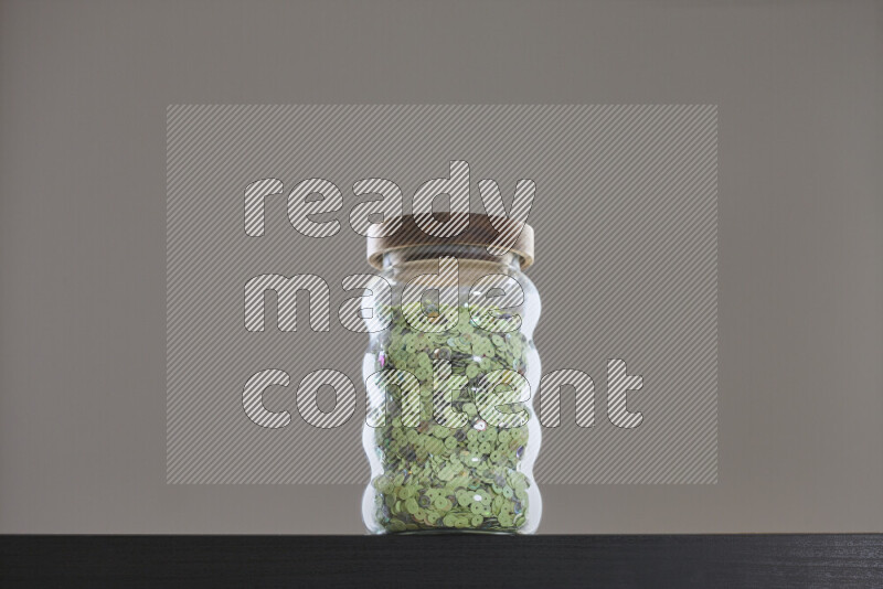Sequins in a glass jar on black background