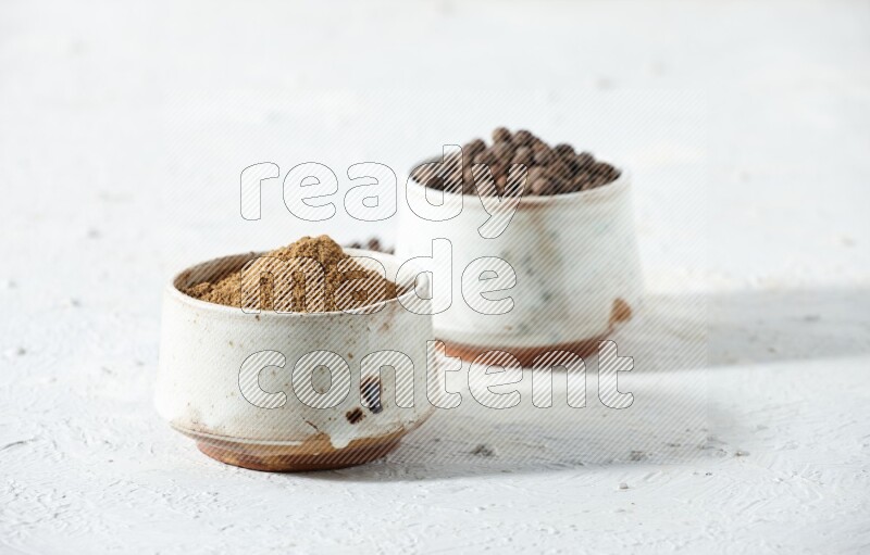 2 beige bowls, one full of powder and the other full of whole balls with balls and powder spreaded on a textured white flooring