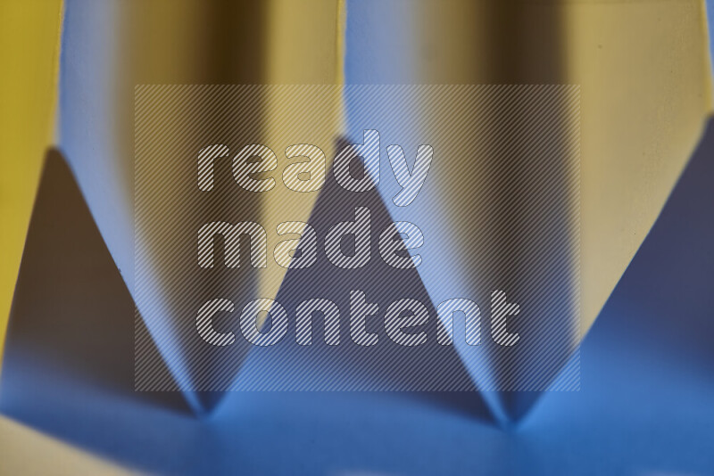 A close-up abstract image showing sharp geometric paper folds in blue gradients and warm tones