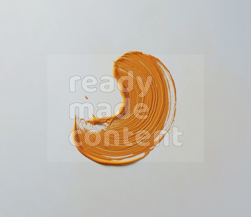 An orange curved painting brush stroke on a white background