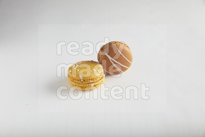 45º Shot of of two assorted Brown Irish Cream, and Yellow Piña Colada macarons on white background