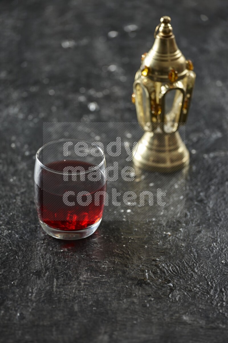 A golden lantern with different drinks, dates, nuts, prayer beads and quran on textured black background
