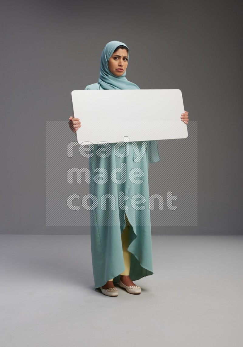 Saudi Woman wearing Abaya standing holding board on Gray background