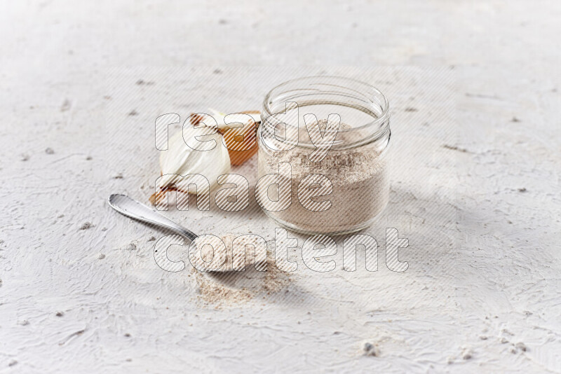 A glass jar full of onion powder on white background