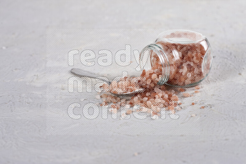 A glass jar full of coarse himalayan salt crystals on white background