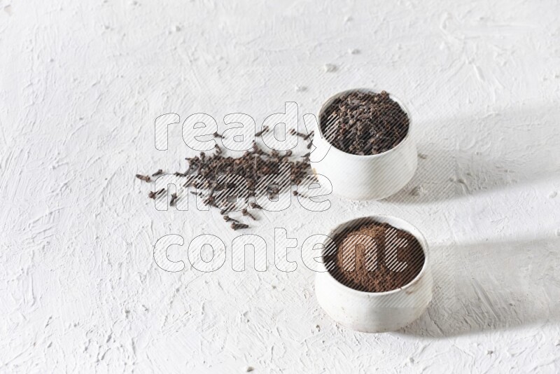 وعاءين من السيراميك بيج اللون، أحدهما مملوء بالقرنفل والآخر مملوء بالبودرة على أرضية بيضاء