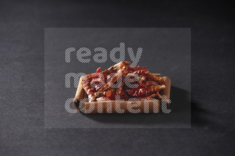 أربعة من أعواد القرفة مكونة شكل مربع بداخلها فلفل حار علي خلفية سوداء