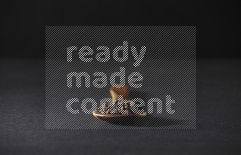 حبوب القرنفل في ملعقة خشبية علي خلفية سوداء