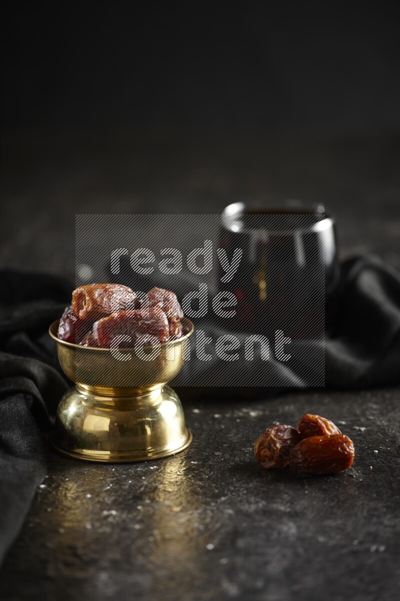 Dried fruits in a metal bowl with tamarind and a napkin in a dark setup