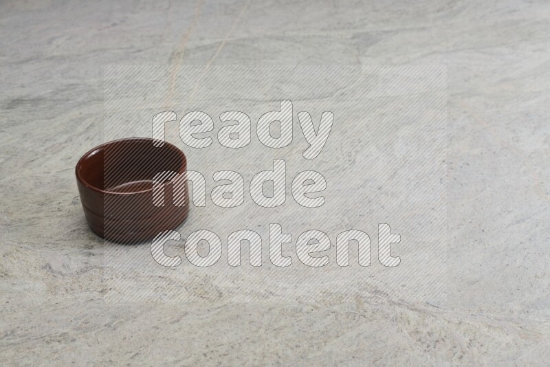A brown pottery bowl on grey marble background