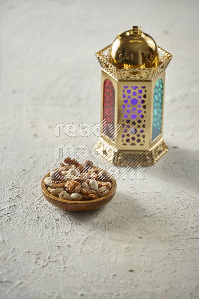 A golden lantern with different drinks, dates, nuts, prayer beads and quran on textured white background