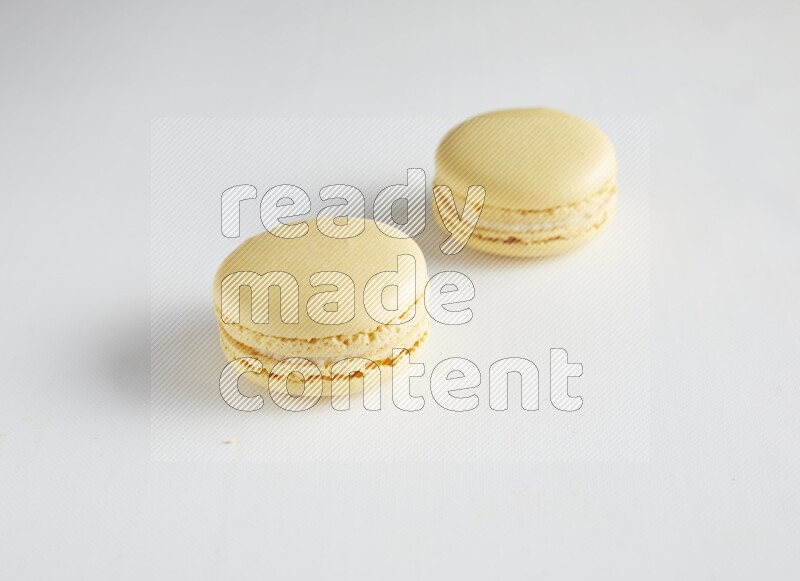 45º Shot of two Yellow Vanilla macarons on white background