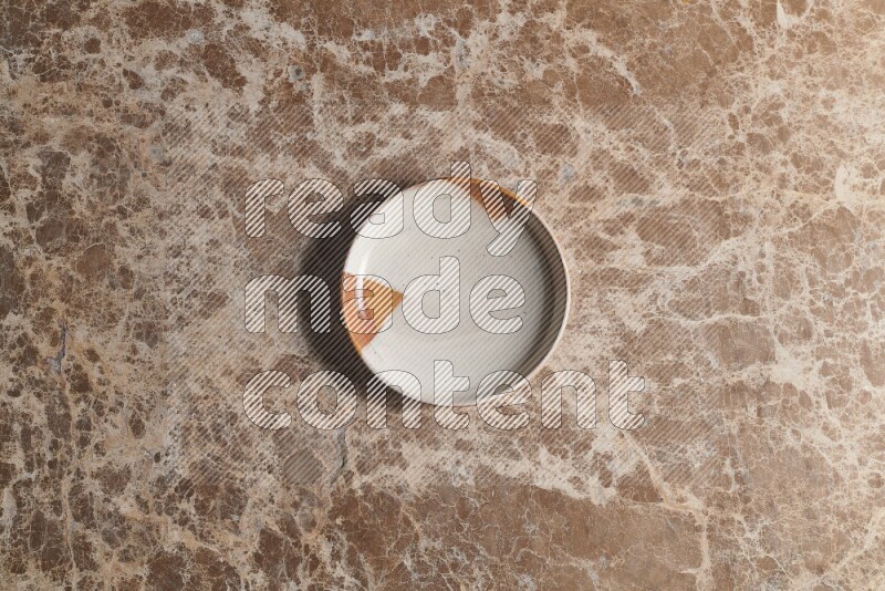 A decorative pottery plate on beige marble background