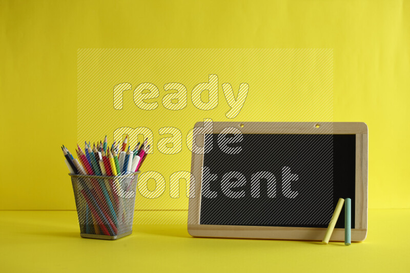 A blackboard with different school supplies on yellow background