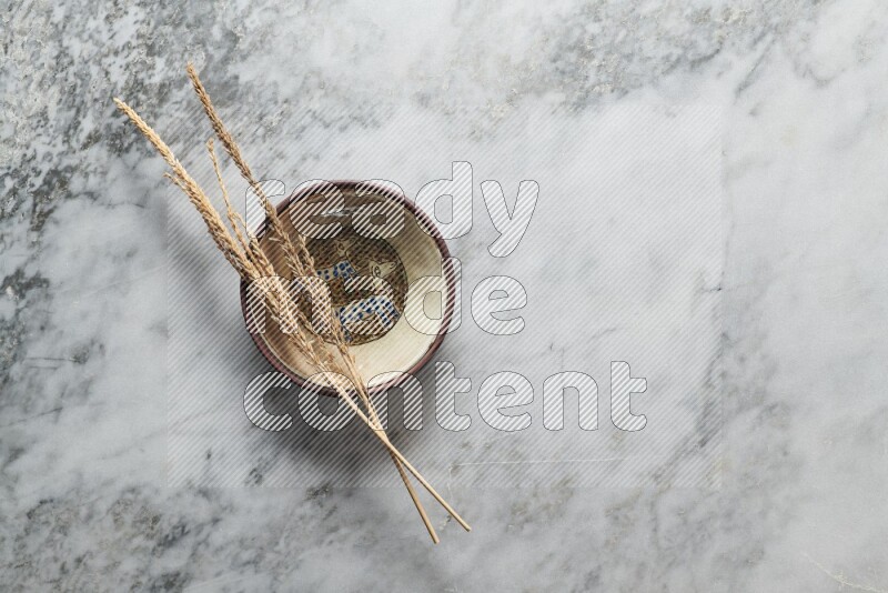 Wheat stalks on decorative pottery plate on grey marble background