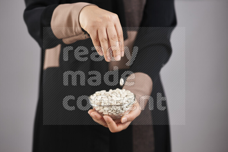 Woman in abaya holding different kinds of legumes in different positions