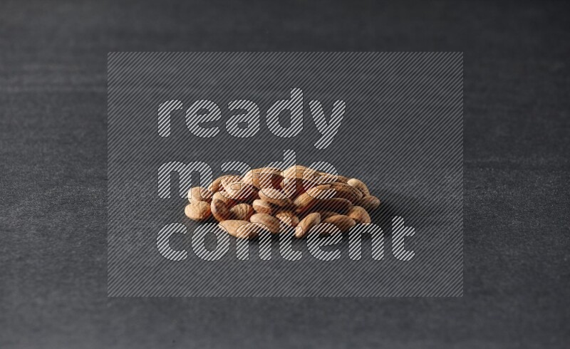 A bunch of peeled almonds on a black background in different angles