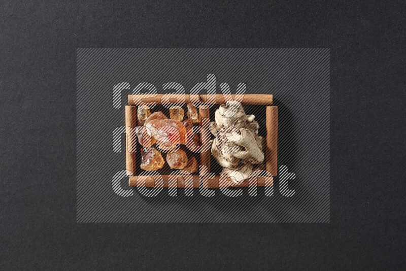 مربعان من أعواد القرفة ممتلئان بالزنجبيل المجفف والصمغ العربي علي خلفية سوداء