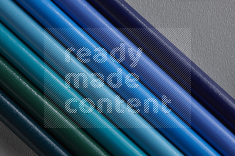 مجموعة من أقلام الرصاص الملونة مرتبة لتعرض تدرجا من الألوان الزرقاء علي خلفية رمادية