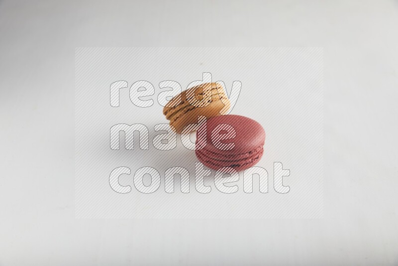 45º Shot of of two assorted Brown Irish Cream, and Red Velvet macarons on white background