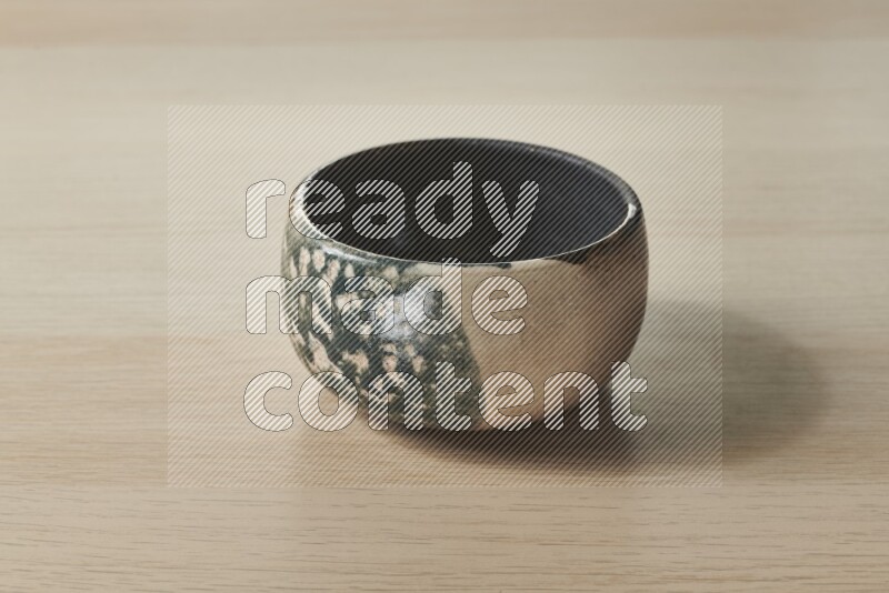 A multicolored pottery bowl on light wooden background