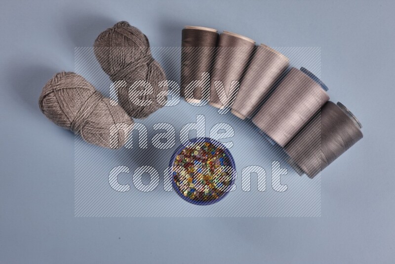 A grey collection of sewing and tailoring tools arranged on a blue background