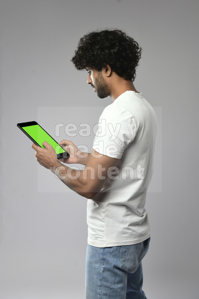 A man wearing casual standing and browsing on a tablet on white background