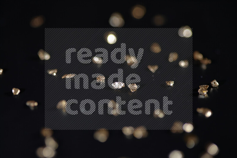 Gold shimmering fragments of glass scattered on a black background