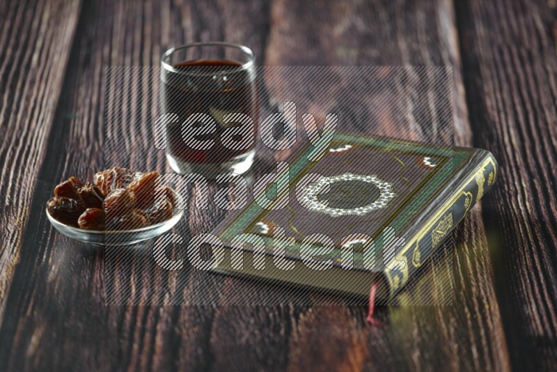 Quran with dates, prayer beads and different drinks all placed on wooden background