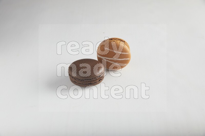 45º Shot of of two assorted Brown Irish Cream, and Brown Dark Chocolate macarons on white background