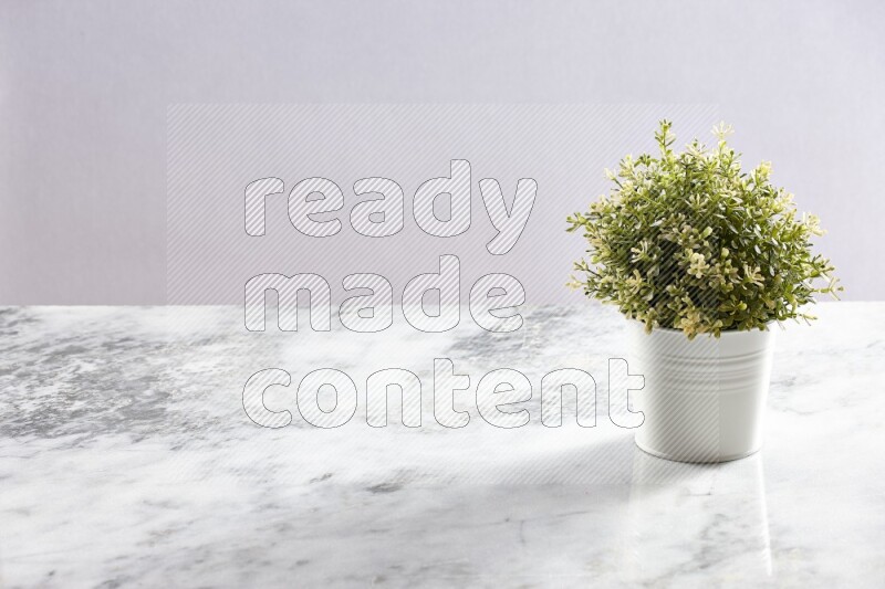 Artificial plant in white pot on grey marble background