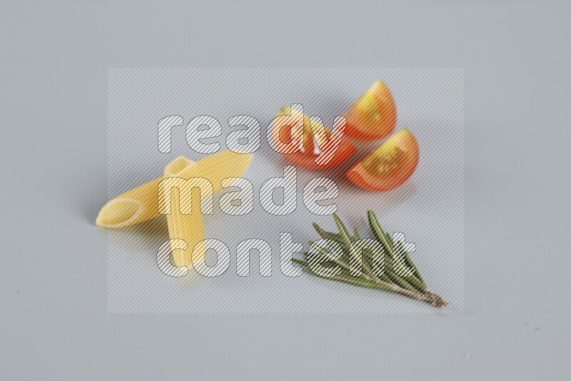 Raw pasta with different ingredients such as cherry tomatoes, garlic, onions, red chilis, black pepper, white pepper, bay laurel leaves, rosemary, cardamom and mushrooms on light blue background