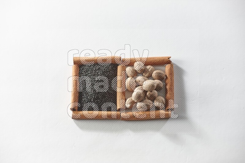2 squares of cinnamon sticks full of black seeds and nutmeg on white flooring