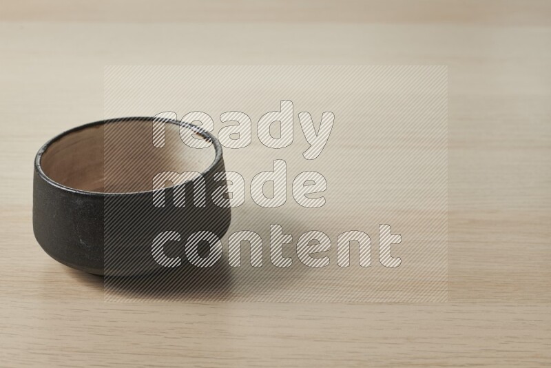 A black pottery bowl on light wooden background