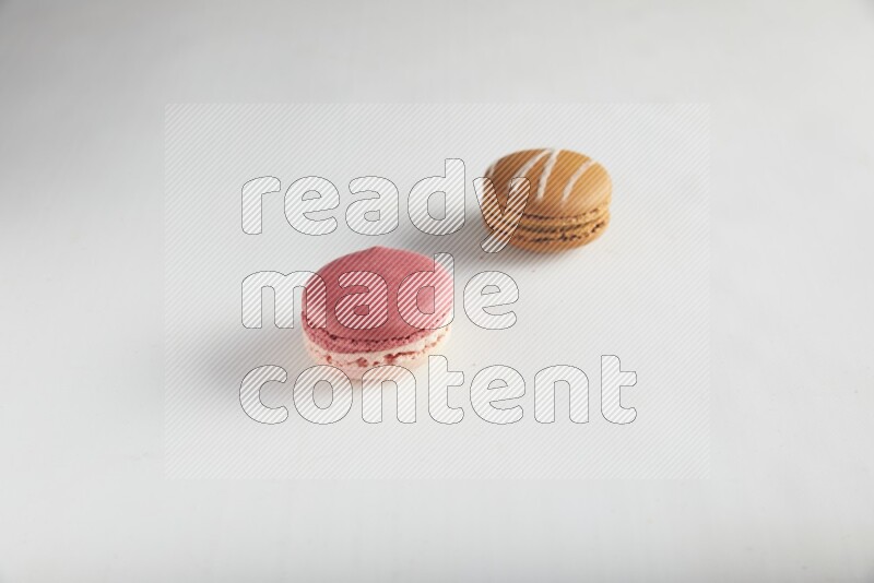 45º Shot of of two assorted Brown Irish Cream, and Pink Litchi Raspberry macarons on white background