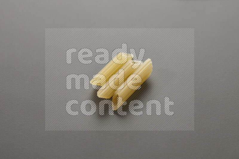 Mini penne pasta on grey background