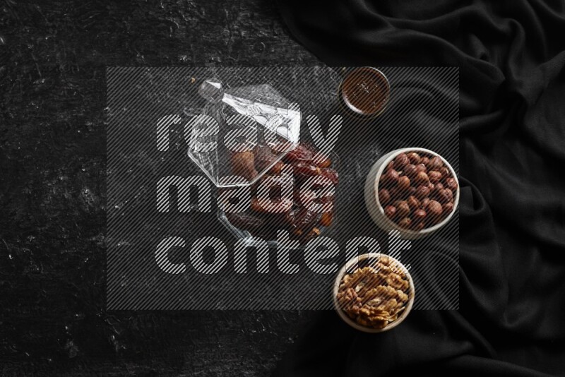 Dates in glass bowl with coffee and nuts in a dark setup