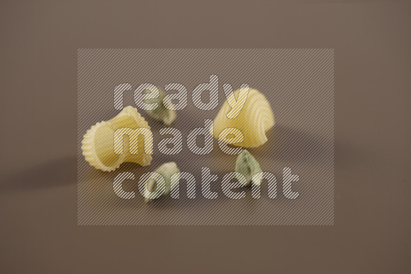 معكرونة مع مكونات متنوعة من الطماطم والثوم والبصل والفلفل الأحمر والفلفل الأسود والفلفل الأبيض وأوراق الغار وإكليل الجبل والهيل على خلفية بيج