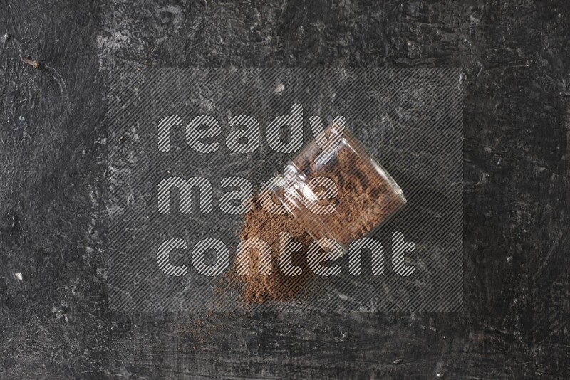 وعاء زجاجي مقلوب ممتلئ ببودرة القرنفل على أرضية سوداء