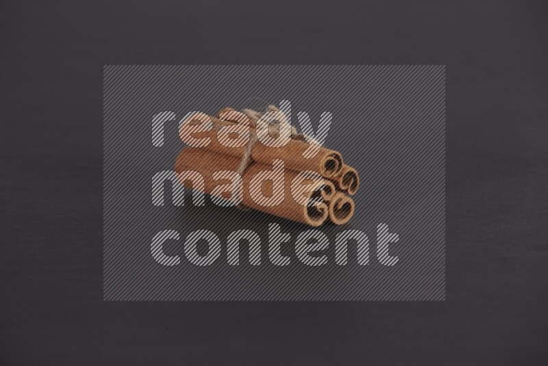 4 أعواد من القرفة مربوطة علي خلفية سوداء