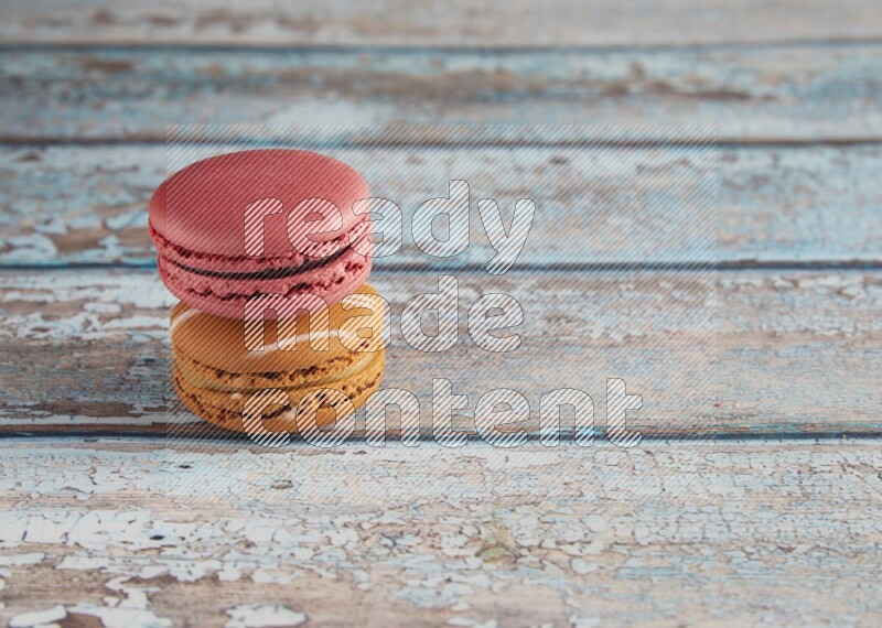 45º Shot of of two assorted Brown Irish Cream, and Pink Raspberry macarons on light blue background