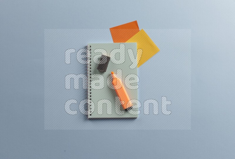 A blue notebook with different school supplies on blue background